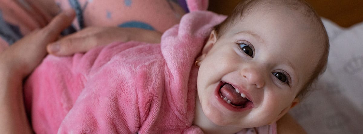 Dentición y fiebre en bebé: Bebé mirando sonriente enseñando los dientes de leche