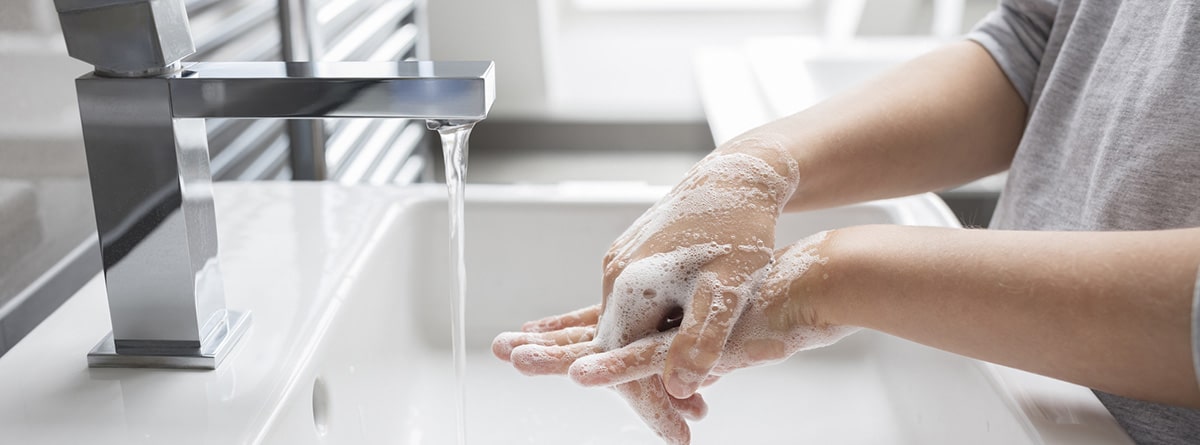Lavarse las manos: manos enlazadas con jabón debajo del grifo de agua