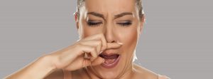 Posibles causas del picor de nariz: Una mujer joven tiene picazón en la nariz sobre fondo blanco.