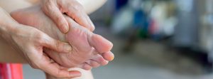Metatarsalgia: mujer sosteniendo un pie con dolor en el metatarso