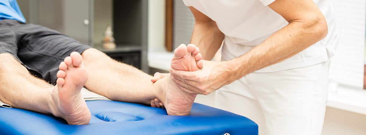 Metatarsalgia curación: fisioterapéuta realizando masajes en el pie de un paciente tumbado en una camilla