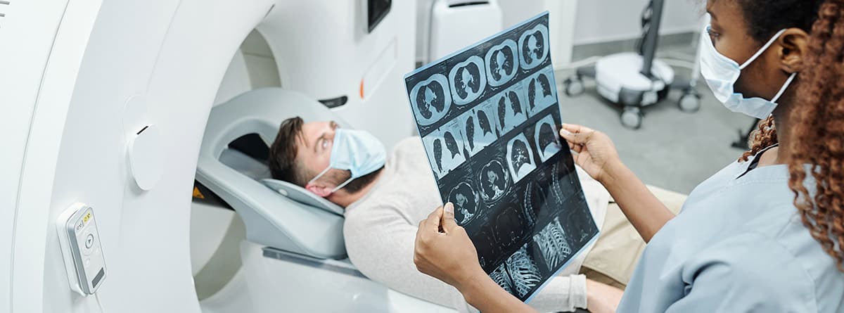Paciente en un aparato de resonancia magnética y mujer especialista mirando las pruebas