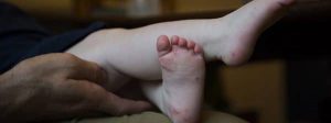 niño con los pies cruzados y ampollas