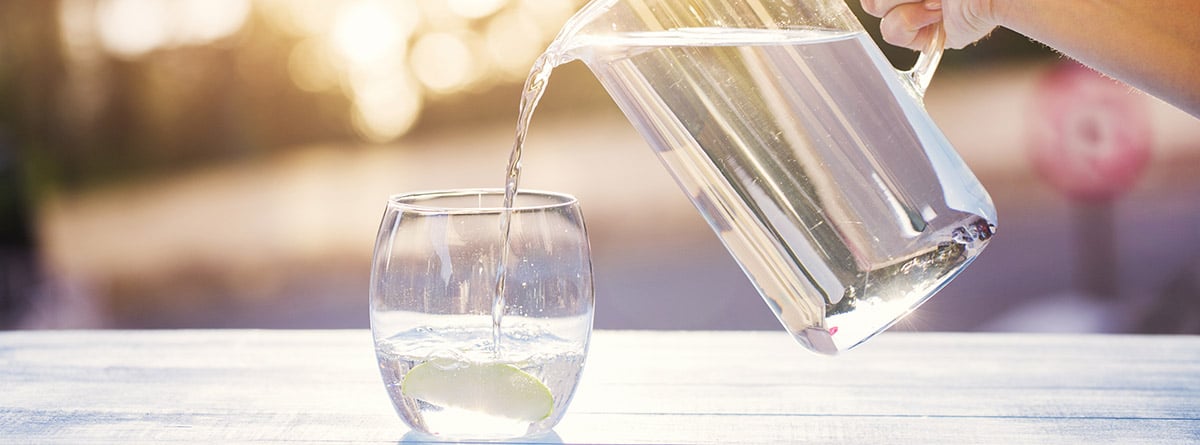 Beber agua al día: jarra de agua y vaso medio lleno