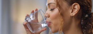 Cuánta agua hay que beber al día: chica joven bebiendo un vaso de agua