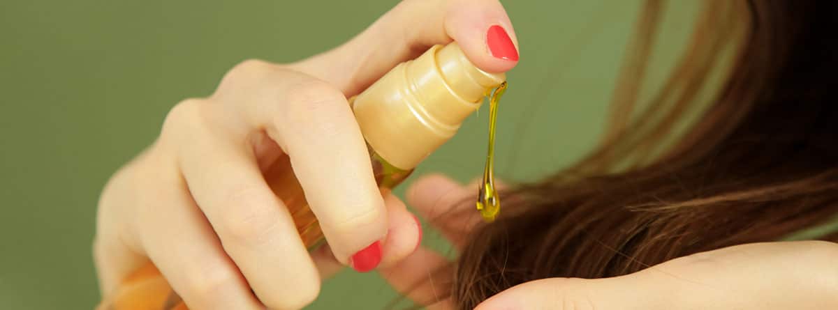 Aceite de argán: mujer con un frasco de aceite de argán echándoselo en el cabello
