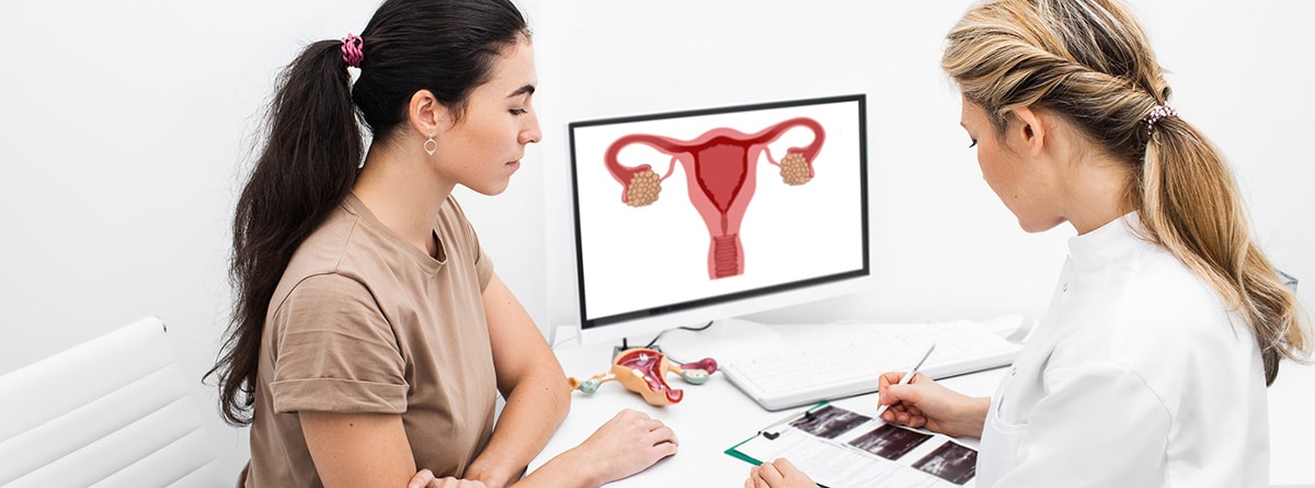 Adenomiosis uterina: mujer en consulta de ginecóloga, con pantalla de ordenador explicando los órganos femeninos
