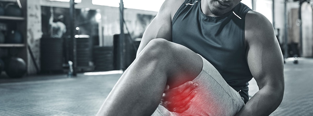 Calambres musculares en deportistas: hombre deportista con un calambre en el muslo