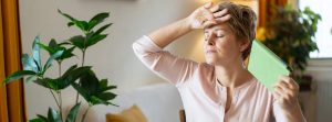 ¿Cómo aliviar los calores súbitos o sofocos?: mujer con la mano en la cabeza y abanicándose con una tablet