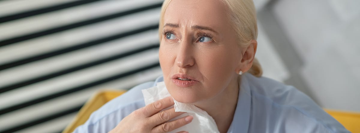Sofocos: mujer rubia quitándose el sudor del cuello con un pañuelo
