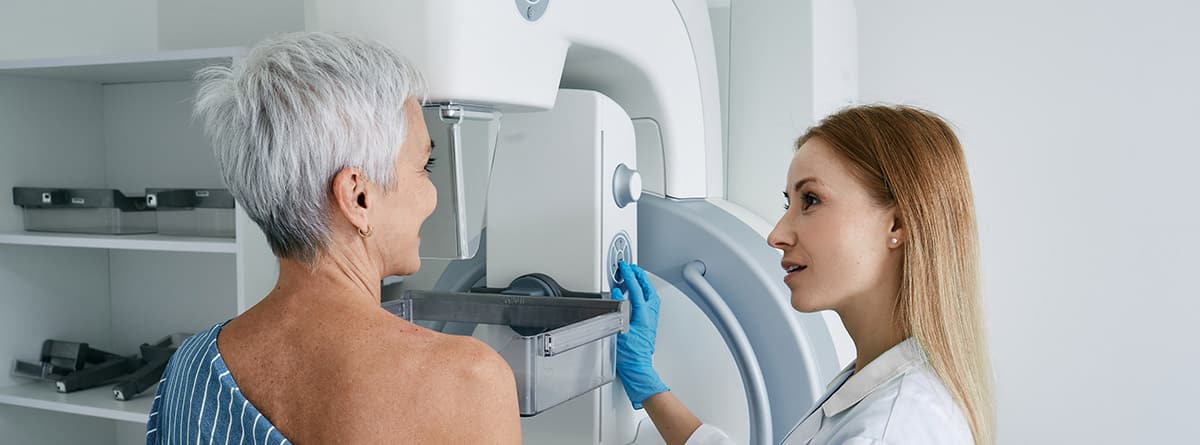 Mamografía y ecografía: mujer en consulta delante de un mamógrafo