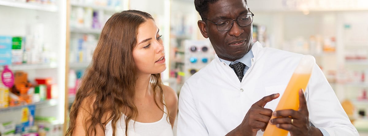 ¿Las siliconas en el champú son buenas? chica joven consultando con el farmacéutico la etiqueta de un champú