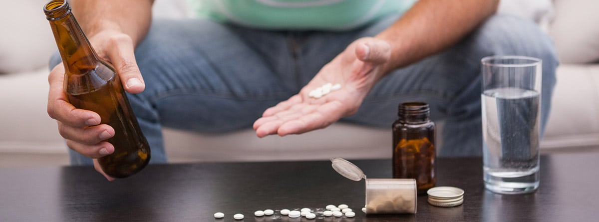 Hombre mezclando cerveza con su medicina sentado en el sofá del salón