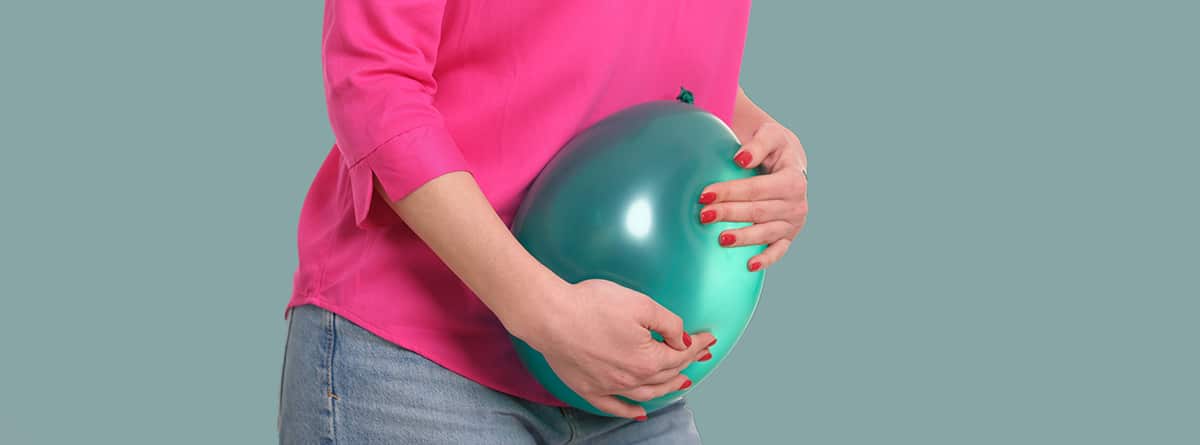 Mujer aprieta un globo verde sobre el abdomen