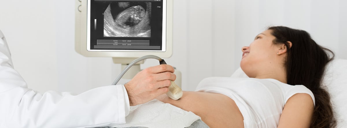 Médico realizando ecografía a una mujer embarazada en la clínica