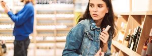 mujer joven con chaqueta vaquera asustada, robando en un supermercado