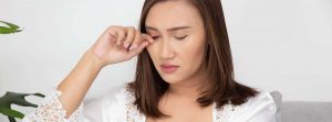 mujer rascándose el ojo por una molestia