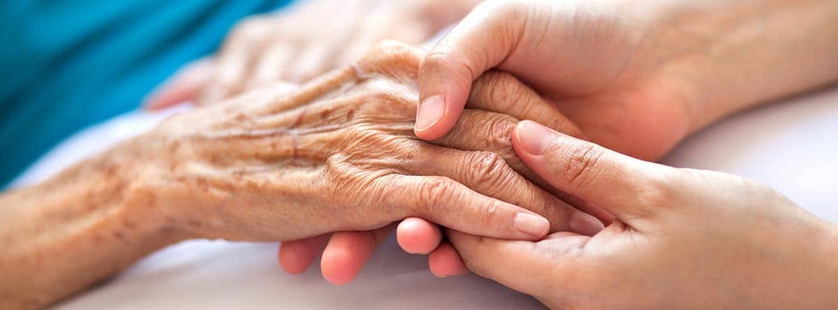 Manos de una persona mayor entrelazadas con otras