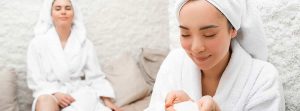 Dos mujeres con albornoz blanco y toalla den la cabeza recibiendo una sesión de haloterapia