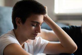 Adolescente con gesto de preocupación con su padre al lado