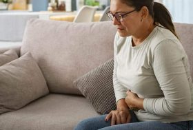 Mujer tocándose la tripa con gesto de dolor
