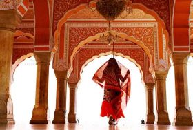 Mujer vestida con traje típico de la India, caminando en un Palacio