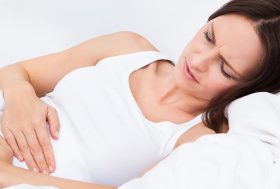 Mujer tumbada en la cama con dolor de vientre