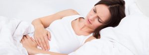 Mujer tumbada en la cama con dolor de vientre
