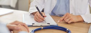 Manos de médico en consulta escribiendo informe médico