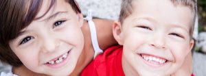 Dos hermanos pequeños con grandes sonrisas y dientes de leche faltantes