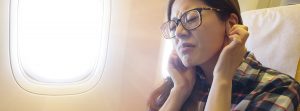 mujer joven con dolor de oídos viajando en avión