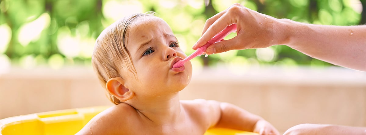 Bebé cepillándose los dientes con ayuda