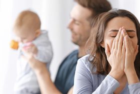Mujer llorando mientras su pareja sostiene al bebé