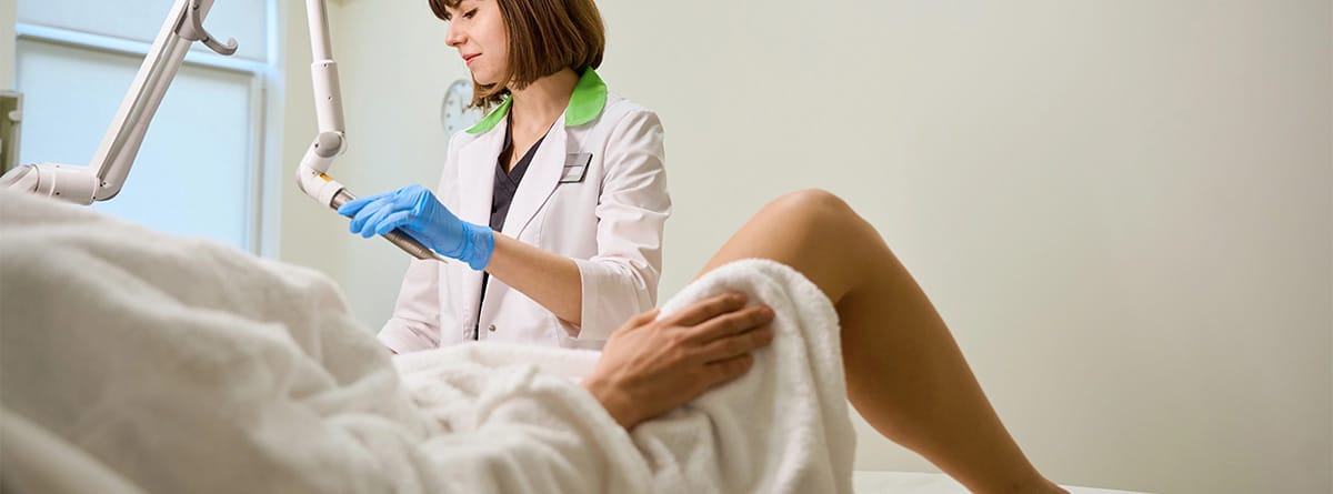 Mujer en consulta ginecológica con la especialista sujetando un aparato de láser