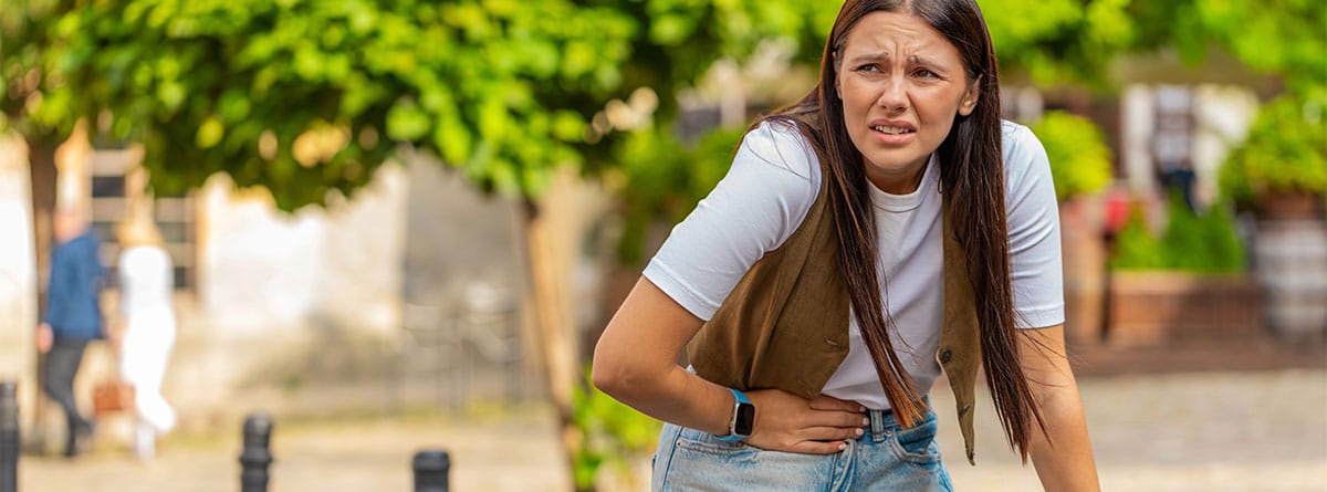 Chica con mochila de viaje con dolor de estómago