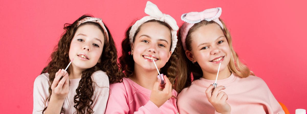 Tres niñas con productos de cosmética para adultos