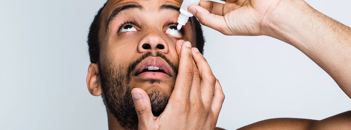 Hombre echándose colirio ojos