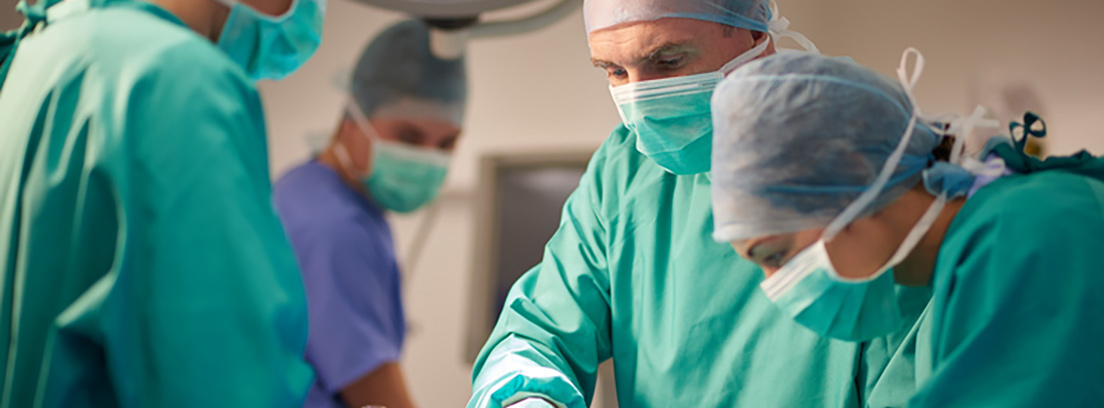 Disección de la aorta. Cirujanos en una sala de operaciones con el traje verde y azul.
