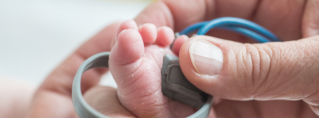 Enfermedades hemorrágicas en bebés El pié de un bebe y las manos de un adulto realizándole una prueba
