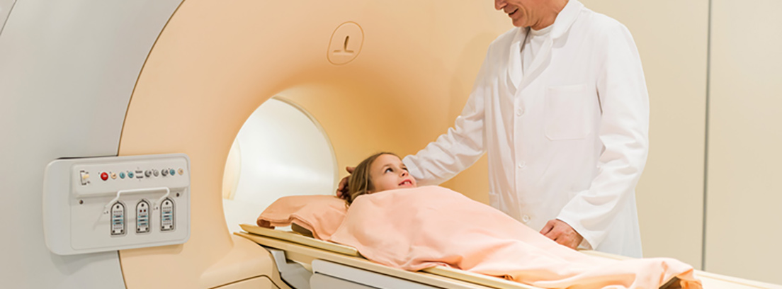 ¿Qué son los linfomas? Niña tapada con una sabana mientras un doctor la mete en un tubo