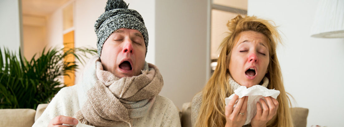 diferencias del resfriado y la gripe pareja en un sofá estornudando y enfermos