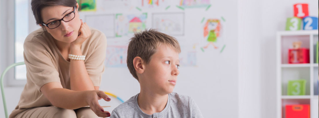 Retraso mental en niños Una mujer observa a un niño que tiene la mirada perdida