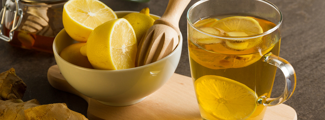 Remedios naturales para la gripe y el resfriado Cuenco con limones y vaso con infusión