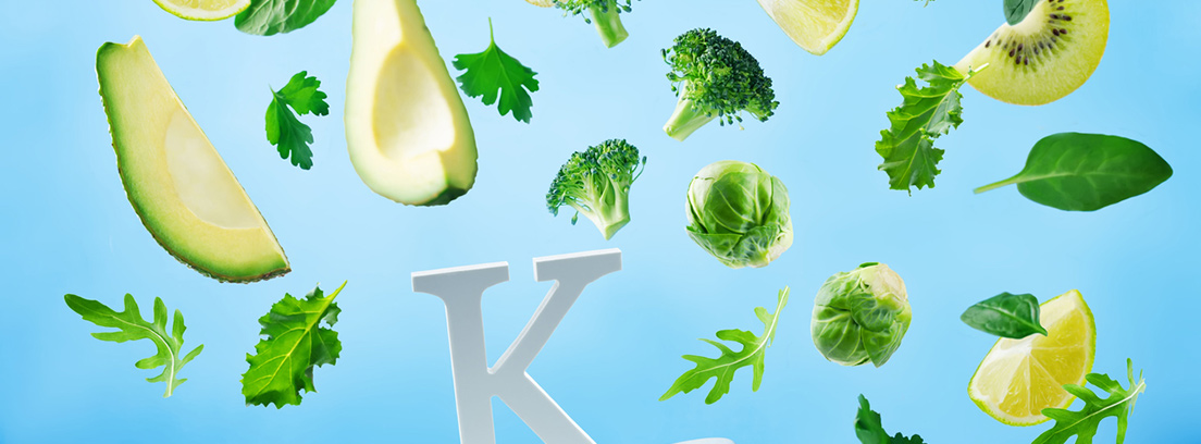 vitamina k trozos de vegatales cayendo sobre una gran letra k