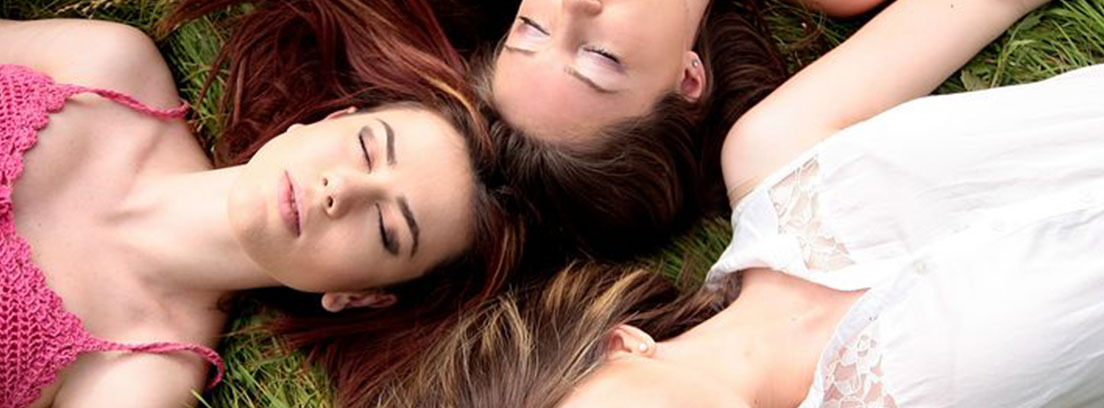 Claves para la buena salud de la mujer Grupo de amigas tumbadas en el césped