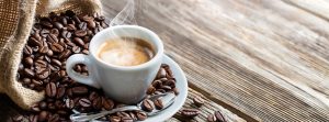 Taza blanca de café caliente con granos de café al lado