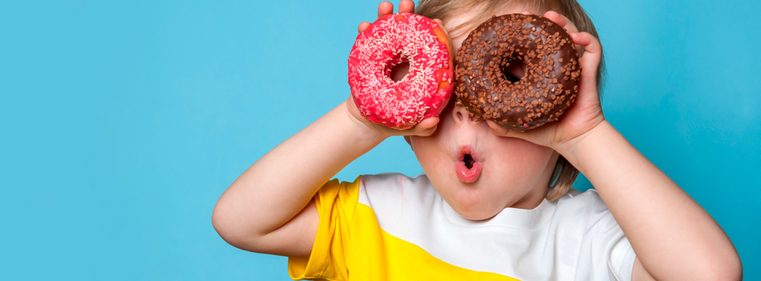 exceso de azúcar en niños dos niños mordiendo un donuts de fresa