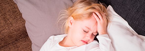 Migrañas infantiles niña tumbada con la mano en la frente