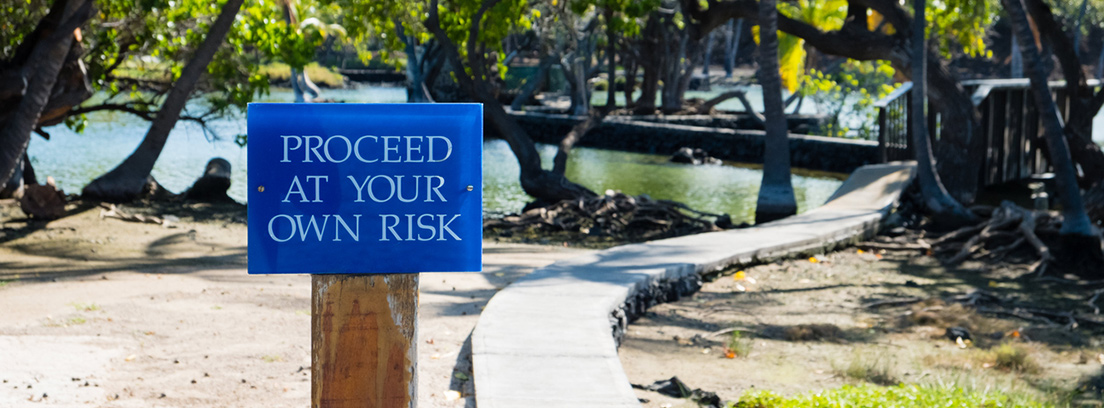 viajes tropicales consejos salud camino con un cartel en ingles y un lago de fondo