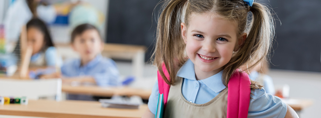 Prepararse para la vuelta al colegio Niña sonriendo con mochila a los hombros en el cole